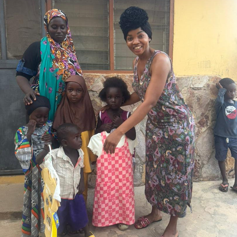 Group of women and children standing together in front of a building receiving clothing donation