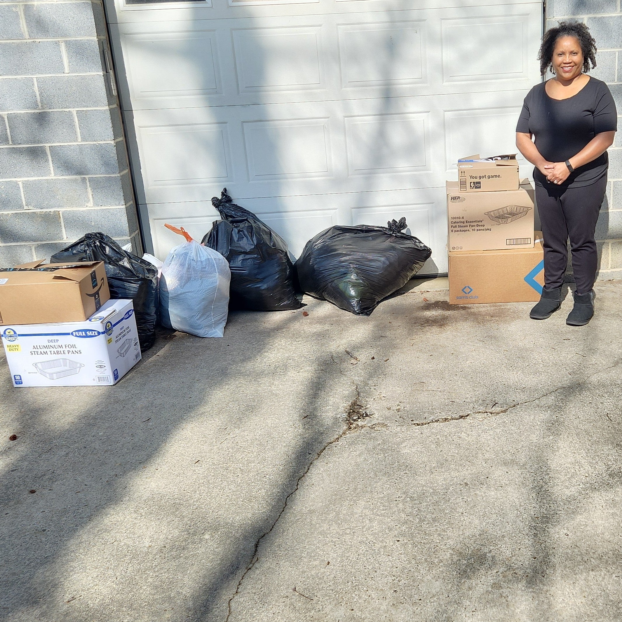 Person standing next to boxes and bags full of clothing donations at Sankofa Drop-Off.